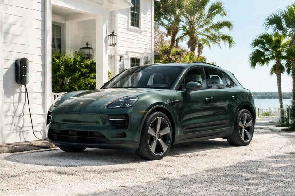 Original AI-generated illustration: Green Porsche Macan Electric-inspired SUV beside a coastal home wall charger